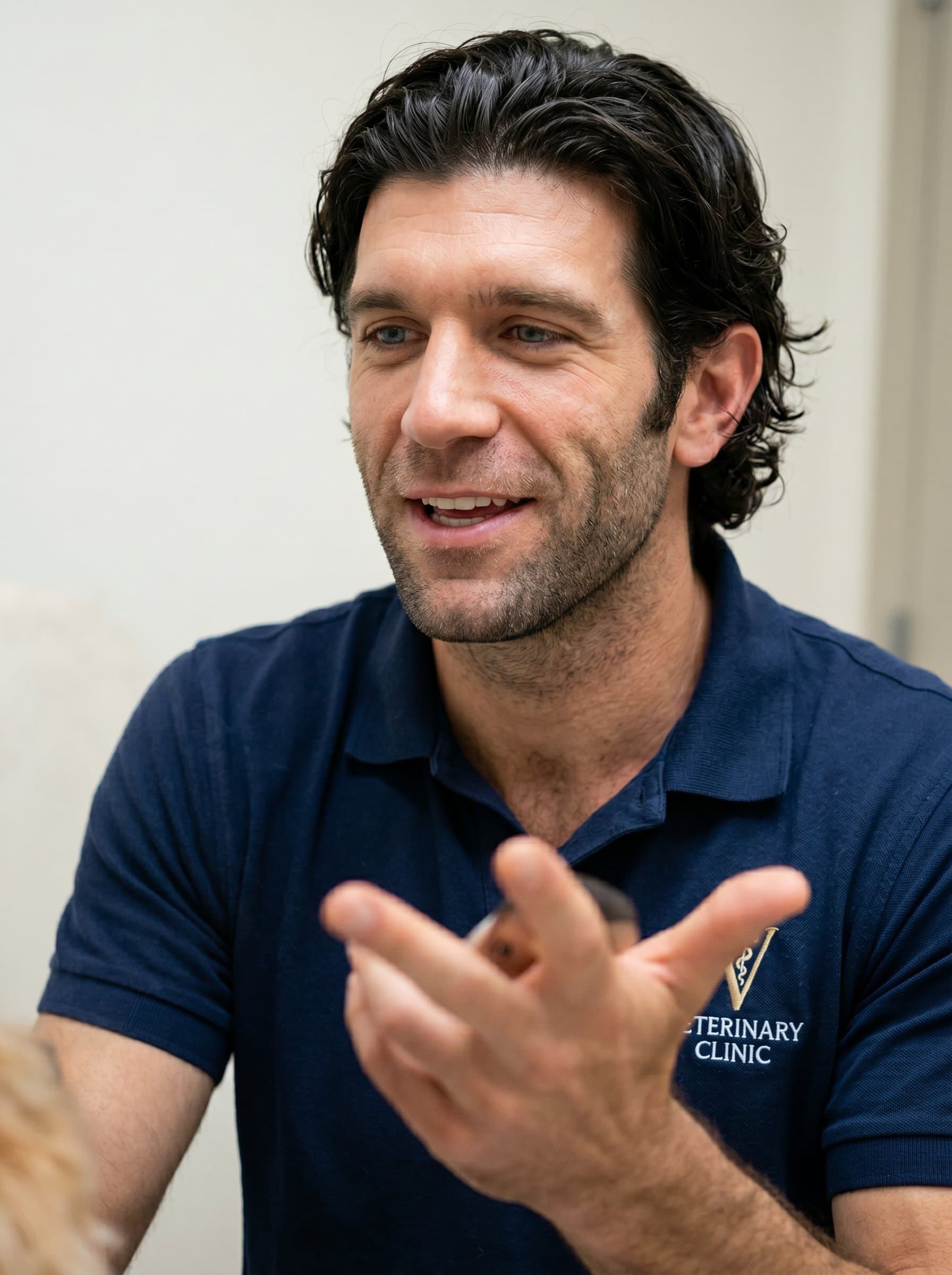 Capture in mid-conversation pose, gesturing toward